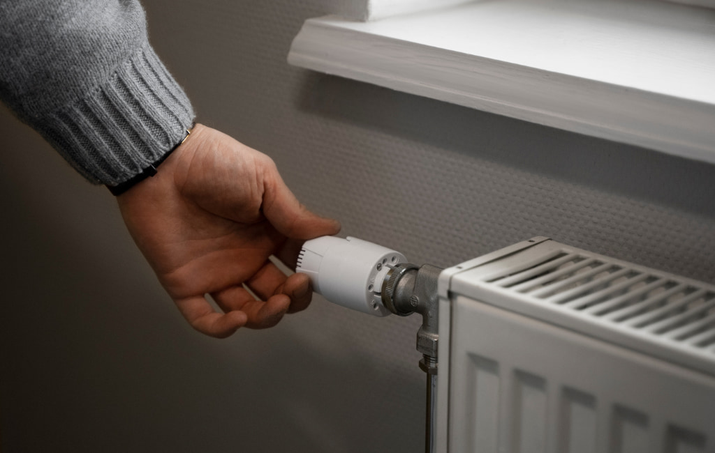 Main réglant un radiateur mural à Hagetmau