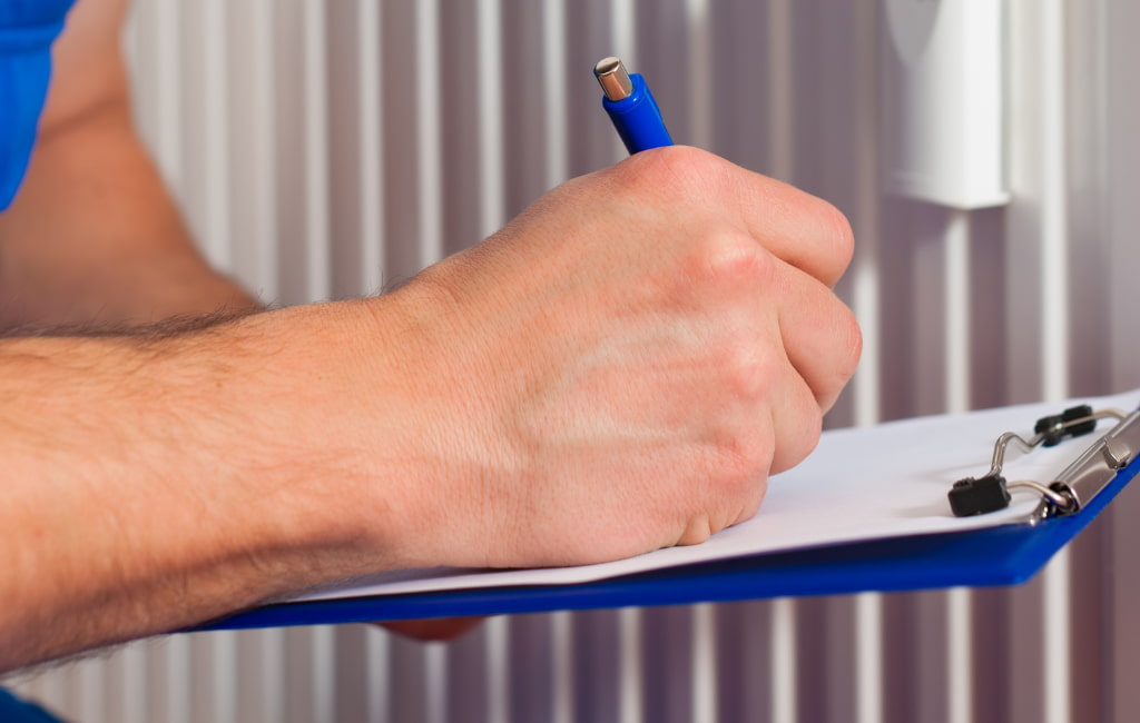 Technicien prenant des notes sur un chauffage à Mont de Marsan